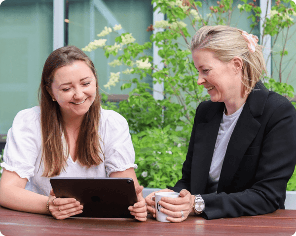 two-women-talking-and-smiling-with-ipad-in-hand